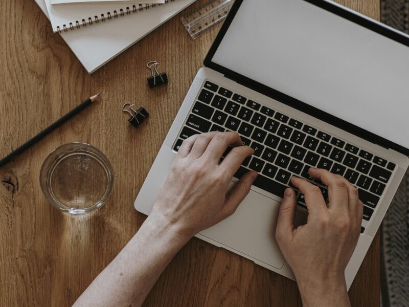 Uśmiechnięta osoba przy laptopie łącząca naukę zarządzania hotelem z odpoczynkiem w domowym zaciszu
